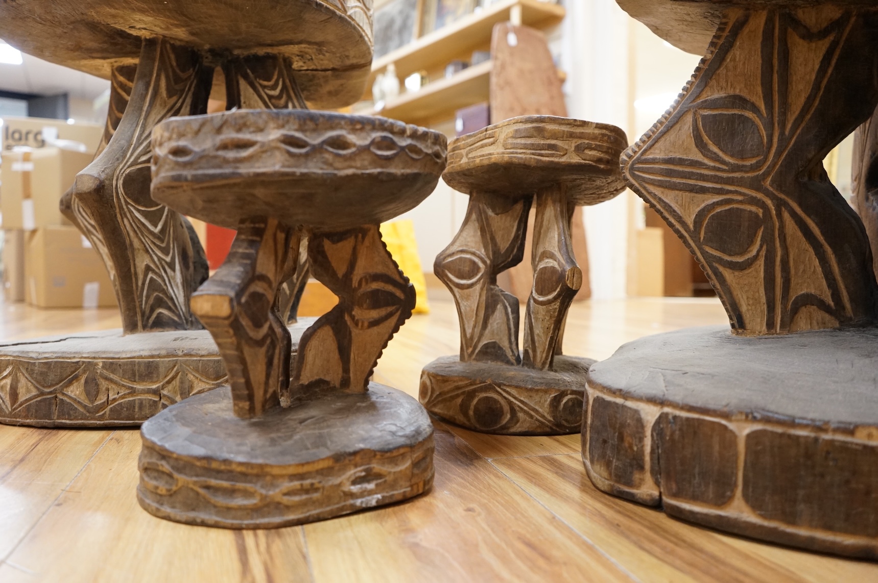 Papua New Guinea Sepik River, two tribal tables, each carved from a section of tree trunk, with circular top and base, the supports and edges incised and painted with geometric designs and two other small stools, largest